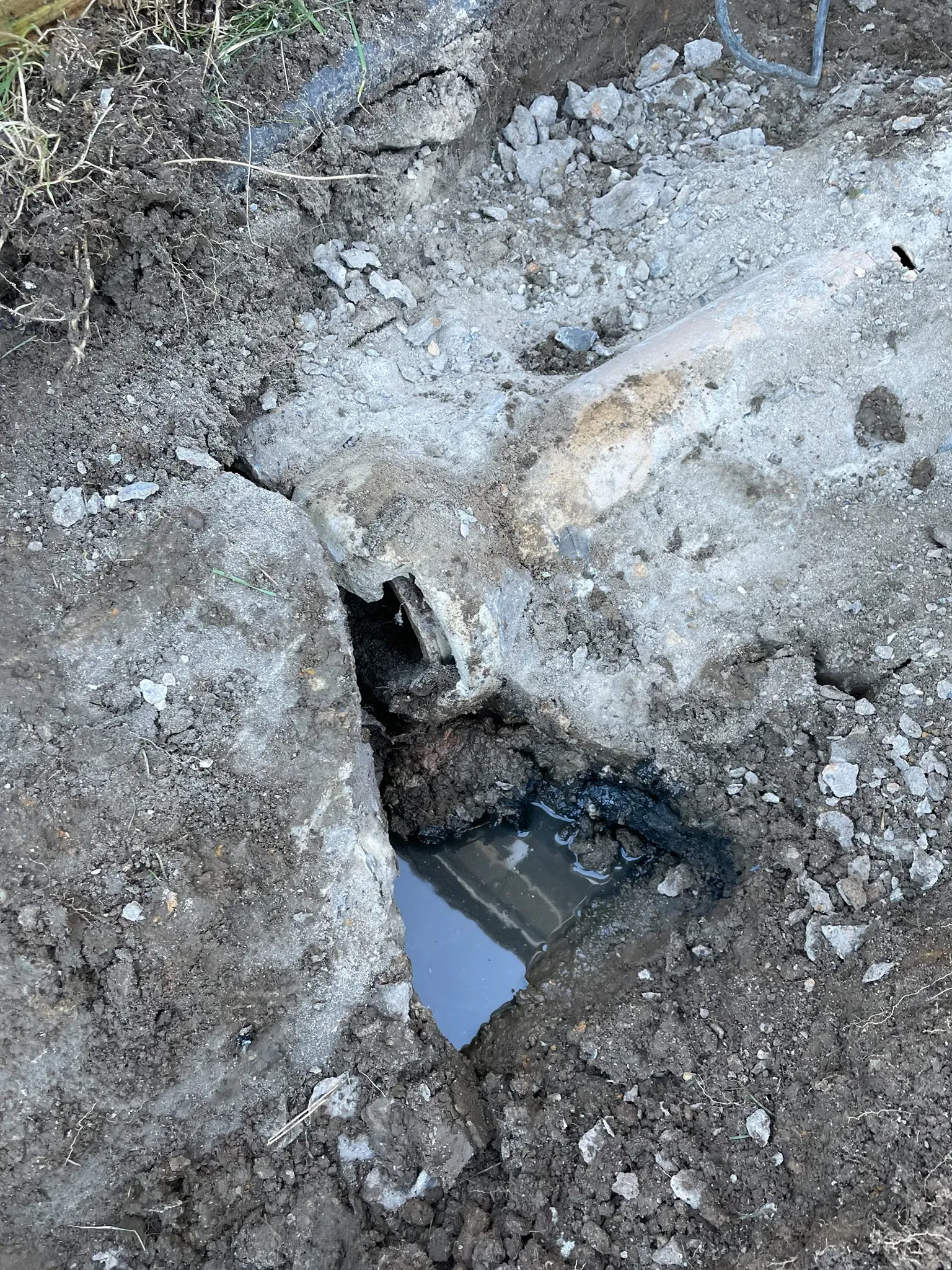 Image of a broken drain pipe in an excavated trench
