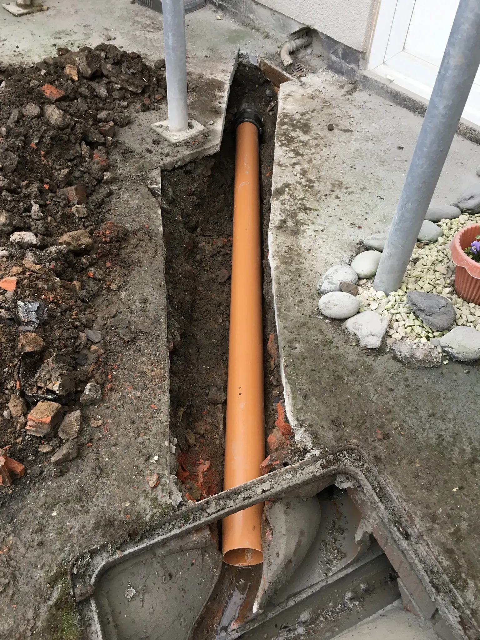 Drain excavation with new orange uPVC pipe being installed by Insta Drain