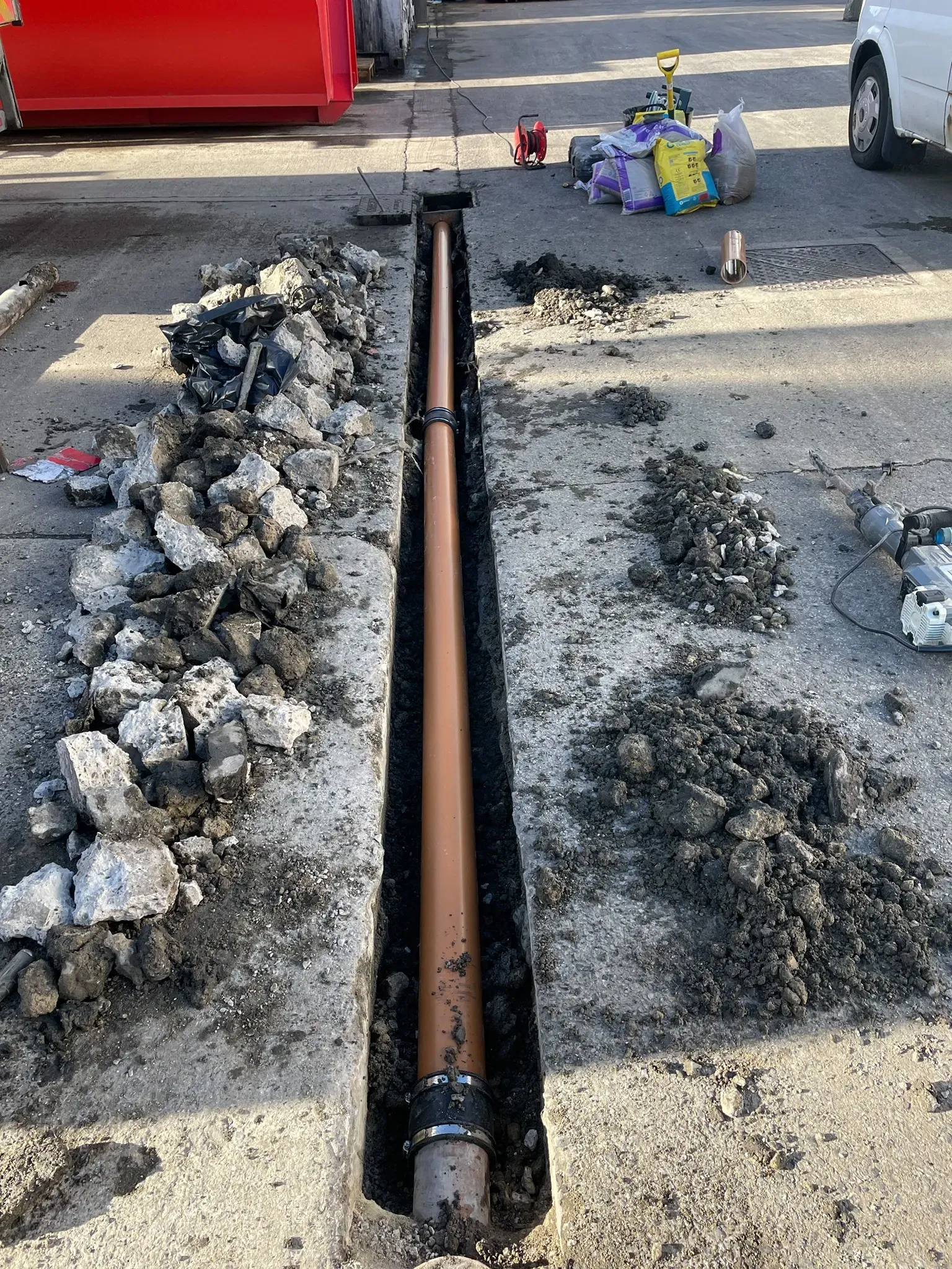 New orange drainage pipe laid in an excavated trench