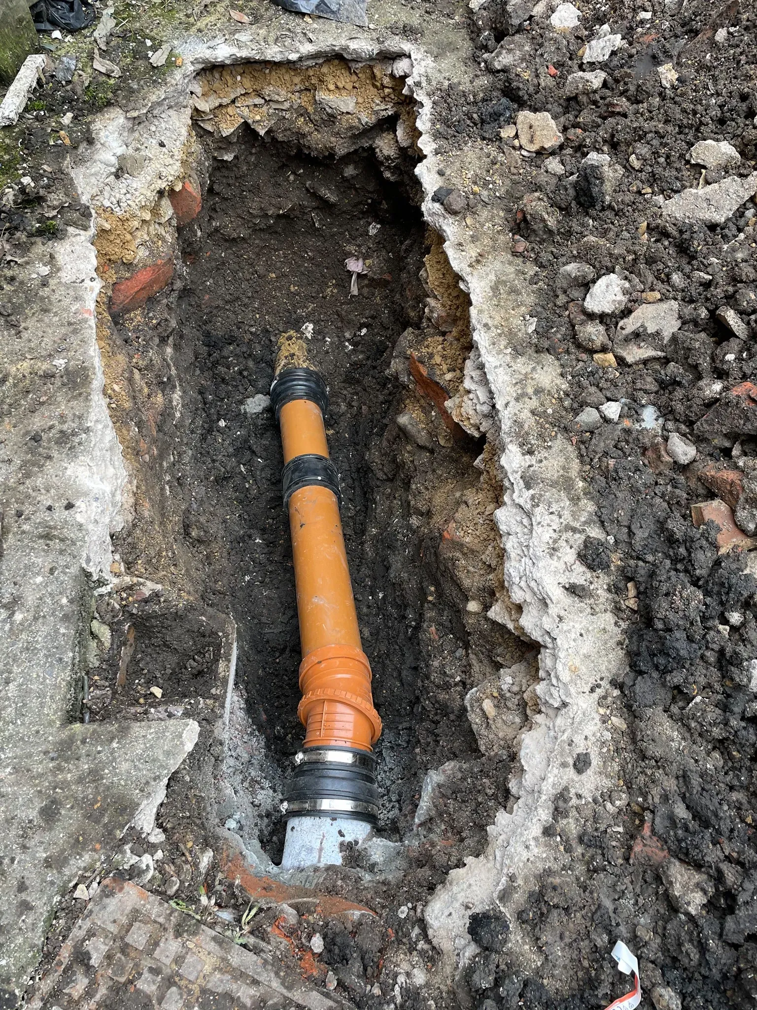 Drain excavation with new orange pipe installed