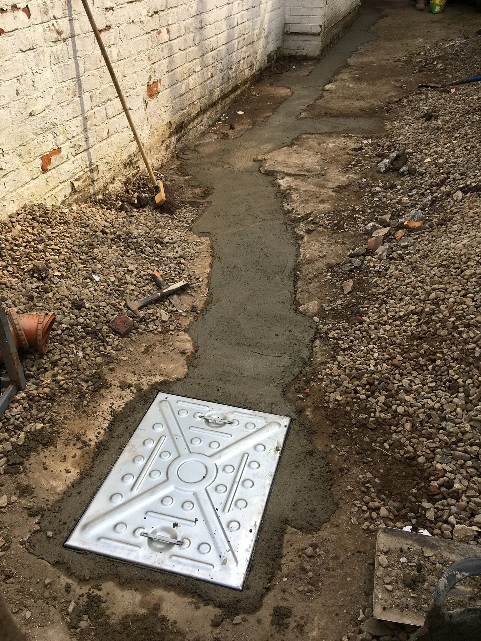 Drainage groundworks featuring a newly set manhole cover in concrete